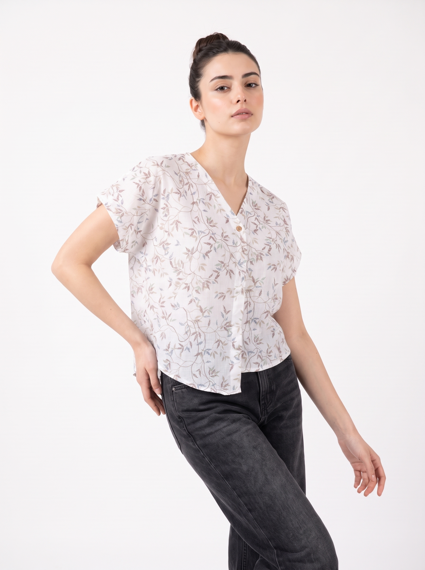 A soft off-white top featuring delicate grey and beige botanical leaf motifs for an elegant, understated look.