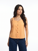 A woman modeling a sleeveless orange and yellow vertically striped top with a button-down front, paired with dark blue jeans, against a plain white studio background.