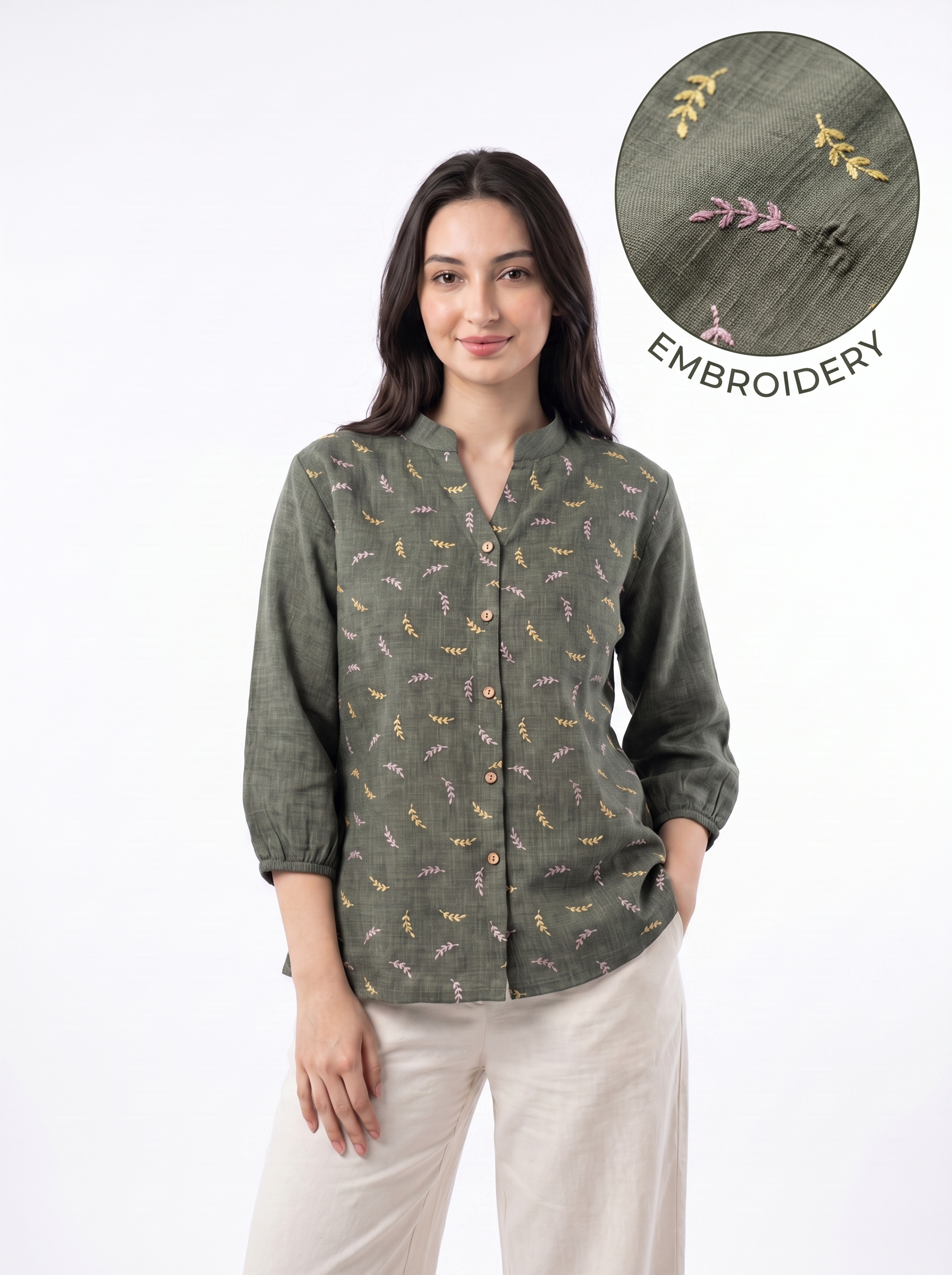 A woman modeling a sage green long-sleeve button-up shirt with a delicate multicolor embroidered pattern, paired with beige trousers. A circular inset in the top right highlights the embroidery detail.