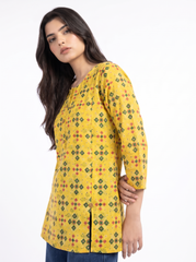 A woman wearing a yellow long-sleeve kurta with a green and red geometric pattern, photographed against a plain white studio background.