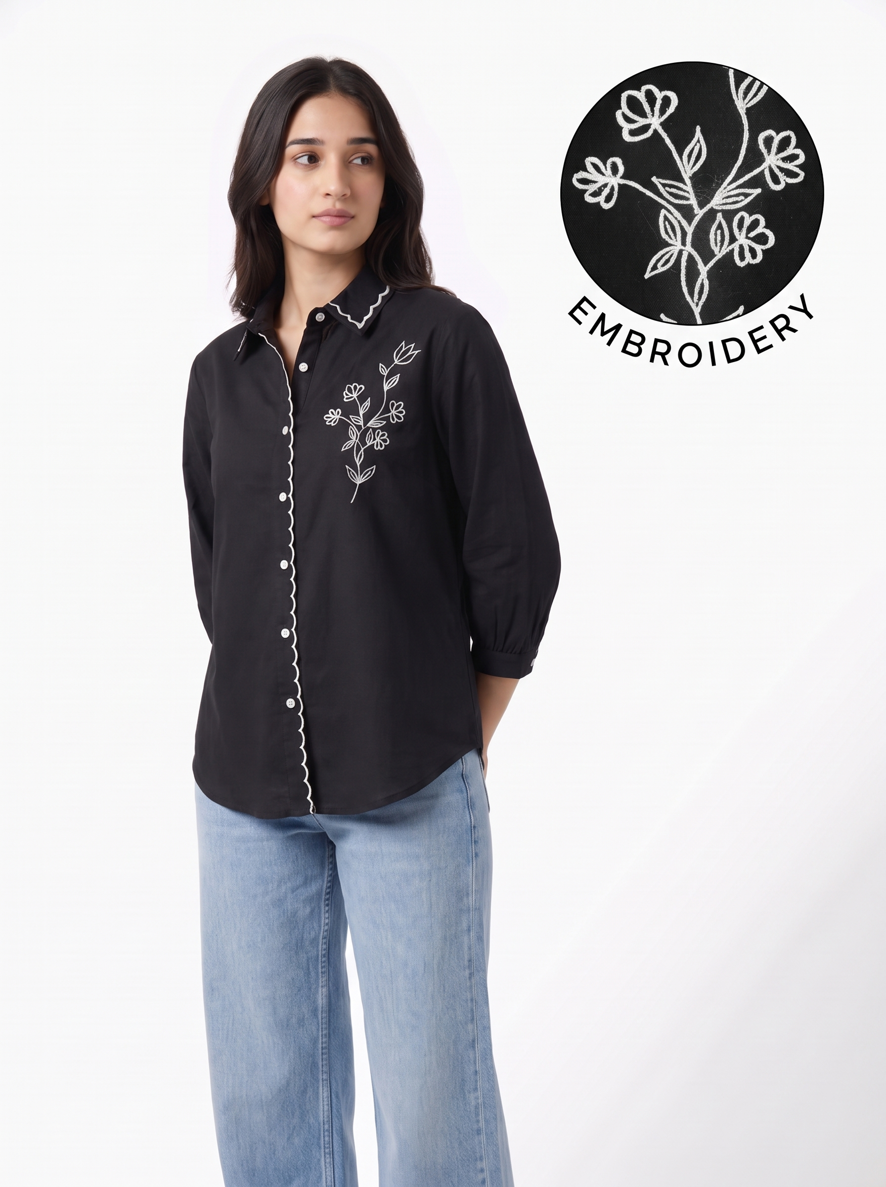 A woman modeling a black long-sleeve button-up shirt with white floral embroidery and white piping along the front placket, paired with light blue jeans. A circular graphic overlay in the top right shows a close-up of the white floral embroidery on black, labeled 'EMBROIDERY'.