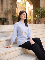 A fresh sky blue top featuring delicate mustard floral embroidery for a subtle contrast. The split neckline, front button detailing, and 3/4 gathered sleeves give it a polished yet easy look.