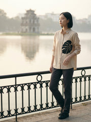 A contemporary cream shirt top featuring a bold black monstera leaf graphic on the front for a clean and artistic statement look.