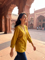 A graceful mustard yellow tunic top featuring elegant off-white floral vine embroidery around the neckline for a refined handcrafted look.