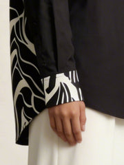 A contemporary beige and black shirt top featuring a striking asymmetric colorblock design with bold floral graphics for a distinctive modern look.