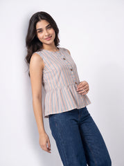 A woman modeling a sleeveless button-front peplum top with vertical peach and blue stripes on a white background, paired with dark blue jeans.