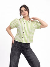 A woman modeling a light green and white vertically striped short-sleeve blouse with a Peter Pan collar and dark buttons, paired with dark gray jeans, against a plain white background.