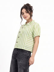 A woman modeling a light green and white vertically striped short-sleeve button-up shirt with dark gray jeans, photographed against a plain white studio background.