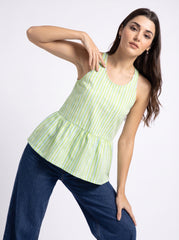 A woman modeling a sleeveless peplum top with a light green and white gingham pattern, paired with dark blue jeans, against a plain white studio background.
