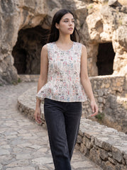 A graceful beige sleeveless top featuring delicate multicolor botanical motifs in soft red, blue, green, and earthy tones