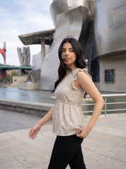 A soft off-white top featuring delicate peach and muted blue floral motifs for a fresh, feminine look.