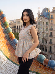 A soft off-white top featuring delicate peach and muted blue floral motifs for a fresh, feminine look.