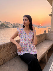 A fresh off-white top featuring soft pink, blue, peach, and green floral motifs for a bright feminine look.