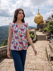A cheerful floral top featuring bold red and pink roses with blue, green, and mustard botanical accents for a fresh feminine look.