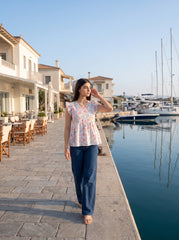 A fresh off-white top featuring soft peach florals with green and blue botanical accents for a charming feminine look.