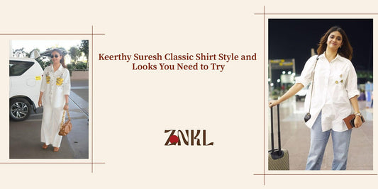 {Keerthy Suresh in a chic white shirt paired with wide-leg pants, accessorized with a statement bag for a classy and effortless look.}-{znkl.in}