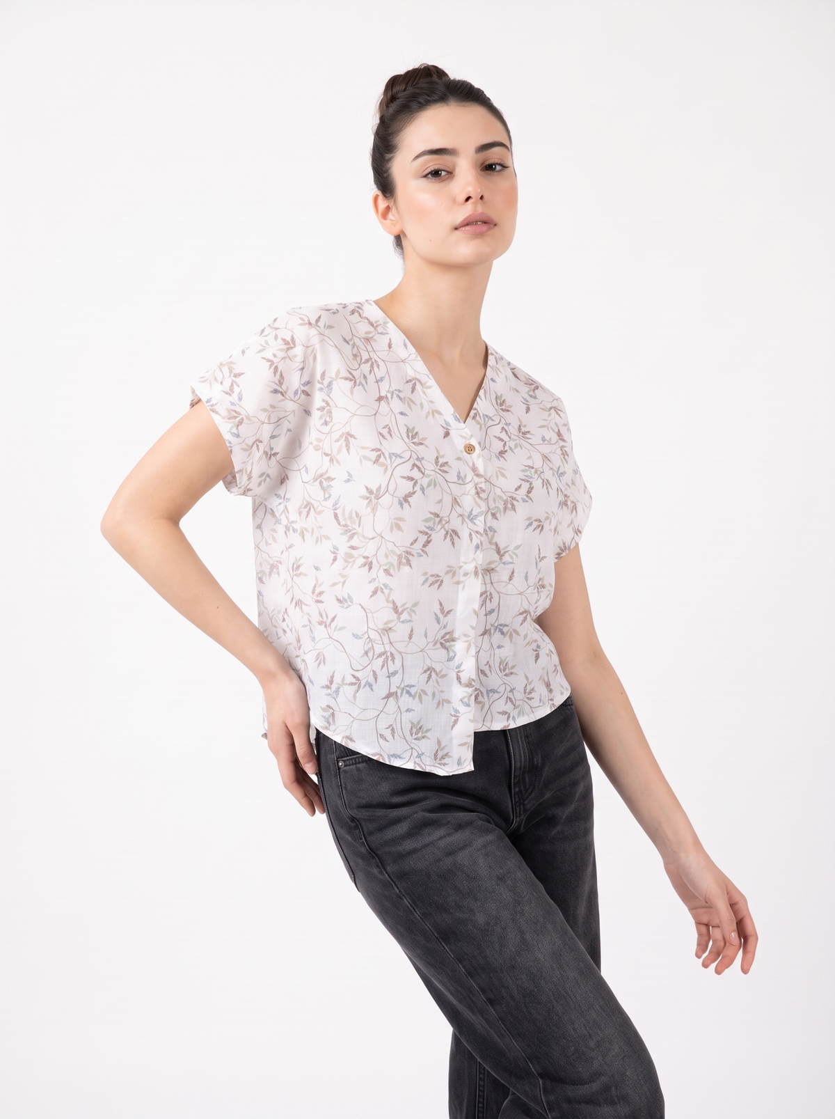 A soft off-white top featuring delicate grey and beige botanical leaf motifs for an elegant, understated look.