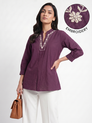 A graceful plum purple tunic top featuring delicate off-white floral vine embroidery around the neckline for an elegant handcrafted touch.