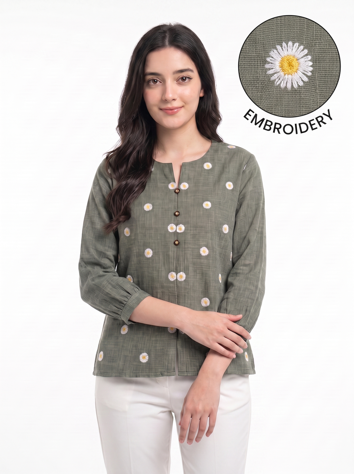 A woman wearing a sage green linen top with white and yellow daisy embroidery, paired with white pants. An inset circle in the top right shows a close-up of the embroidery detail with the text 'EMBROIDERY'.