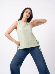 Add a soft feminine touch to your wardrobe with this sage green sleeveless top, featuring delicate multicolor floral embroidery scattered across the front, a clean round neckline, and stylish side tie-up detailing. Its relaxed silhouette and subtle floral accents give it a fresh, effortless appeal, making it perfect for casual outings, brunches, travel, college, and everyday wear.
Style Tip: Pair it with blue denim, white trousers, or beige bottoms and minimal accessories for a fresh everyday look.
