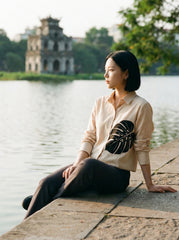 A contemporary cream shirt top featuring a bold black monstera leaf graphic on the front for a clean and artistic statement look. 