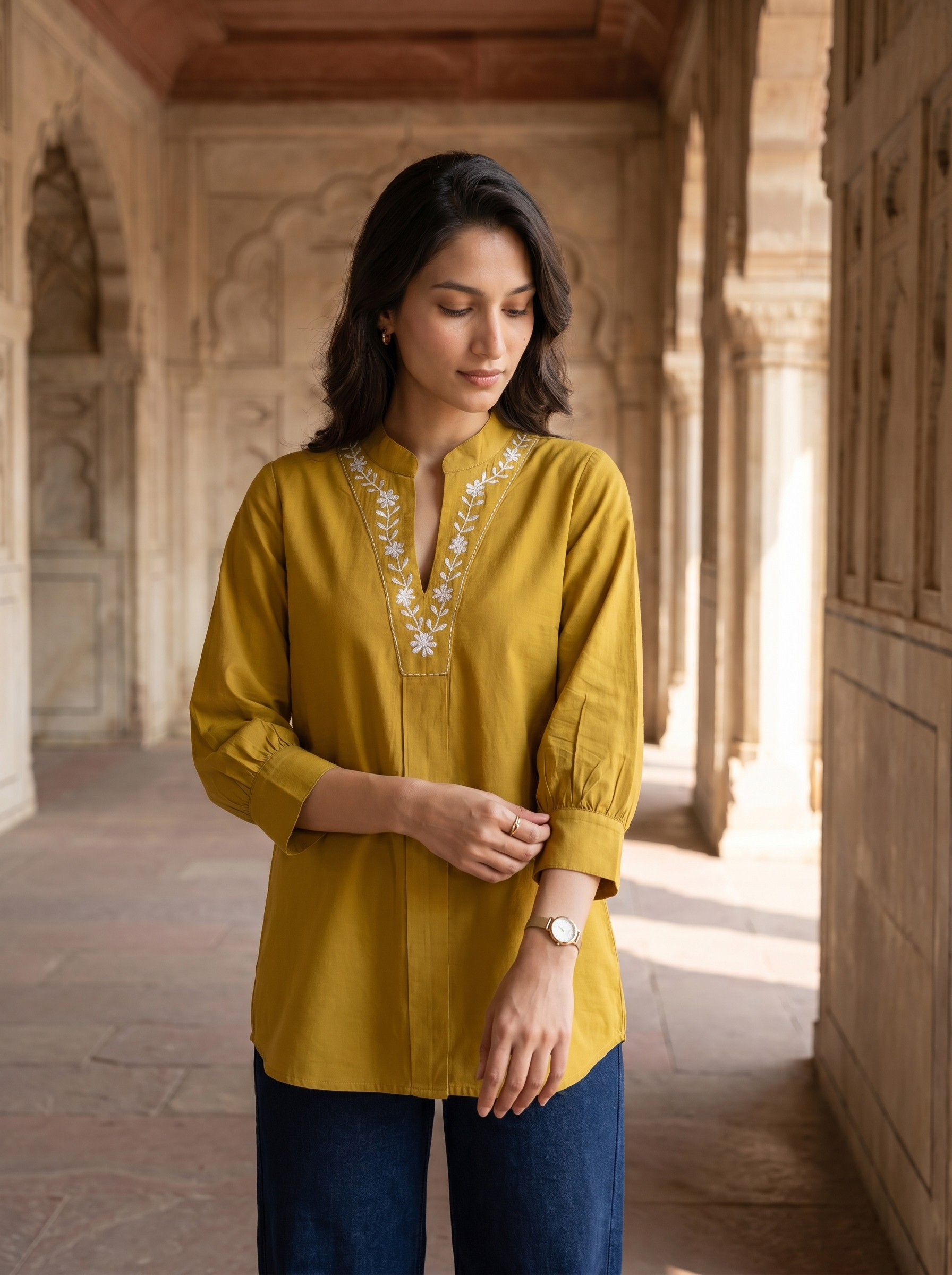A graceful mustard yellow tunic top featuring elegant off-white floral vine embroidery around the neckline for a refined handcrafted look.