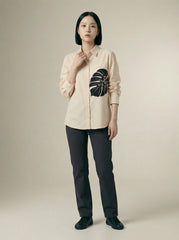 A contemporary cream shirt top featuring a bold black monstera leaf graphic on the front for a clean and artistic statement look. 