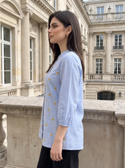A fresh sky blue top featuring delicate mustard floral embroidery for a subtle contrast. The split neckline, front button detailing, and 3/4 gathered sleeves give it a polished yet easy look.