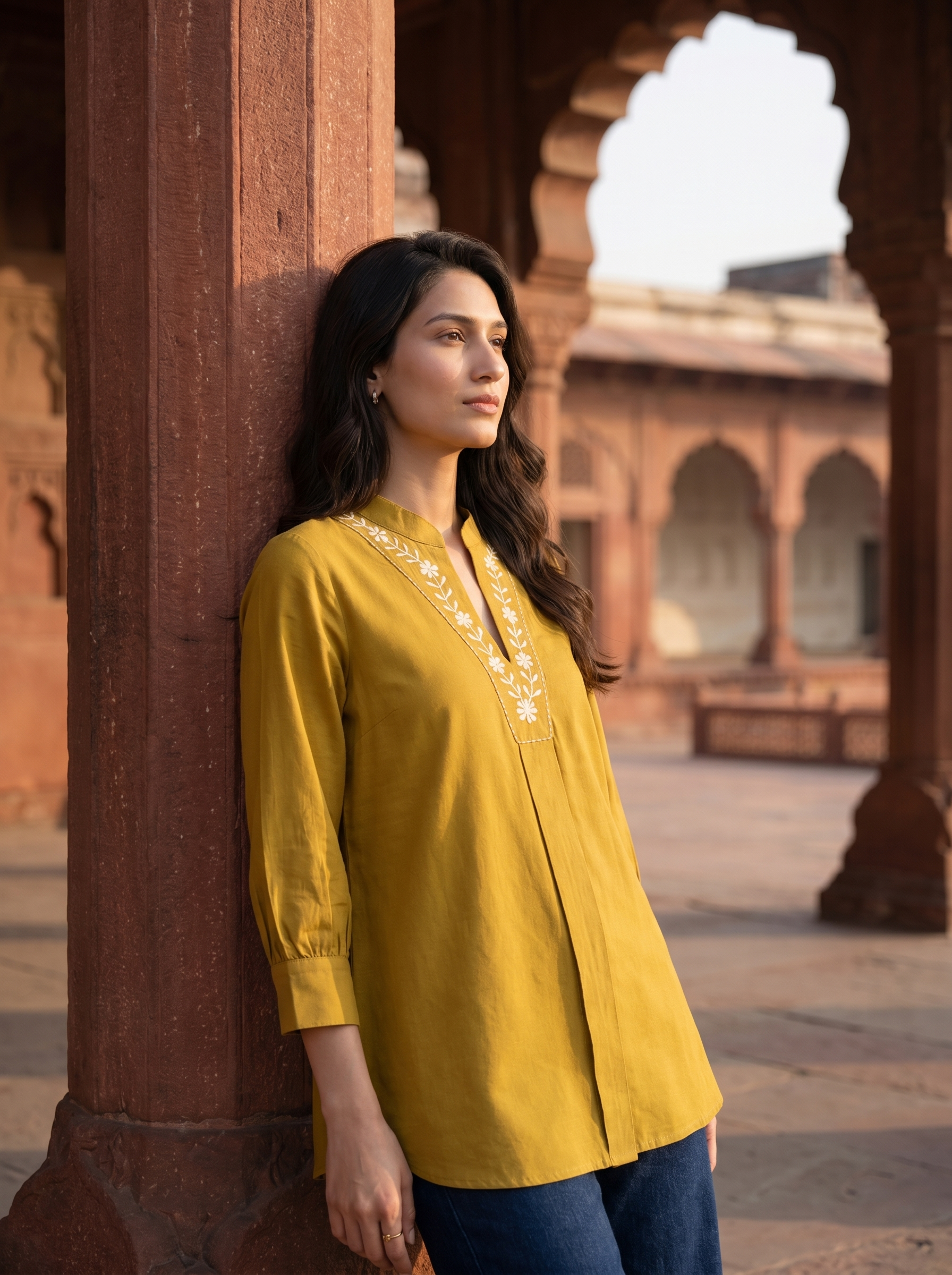 A graceful mustard yellow tunic top featuring elegant off-white floral vine embroidery around the neckline for a refined handcrafted look.