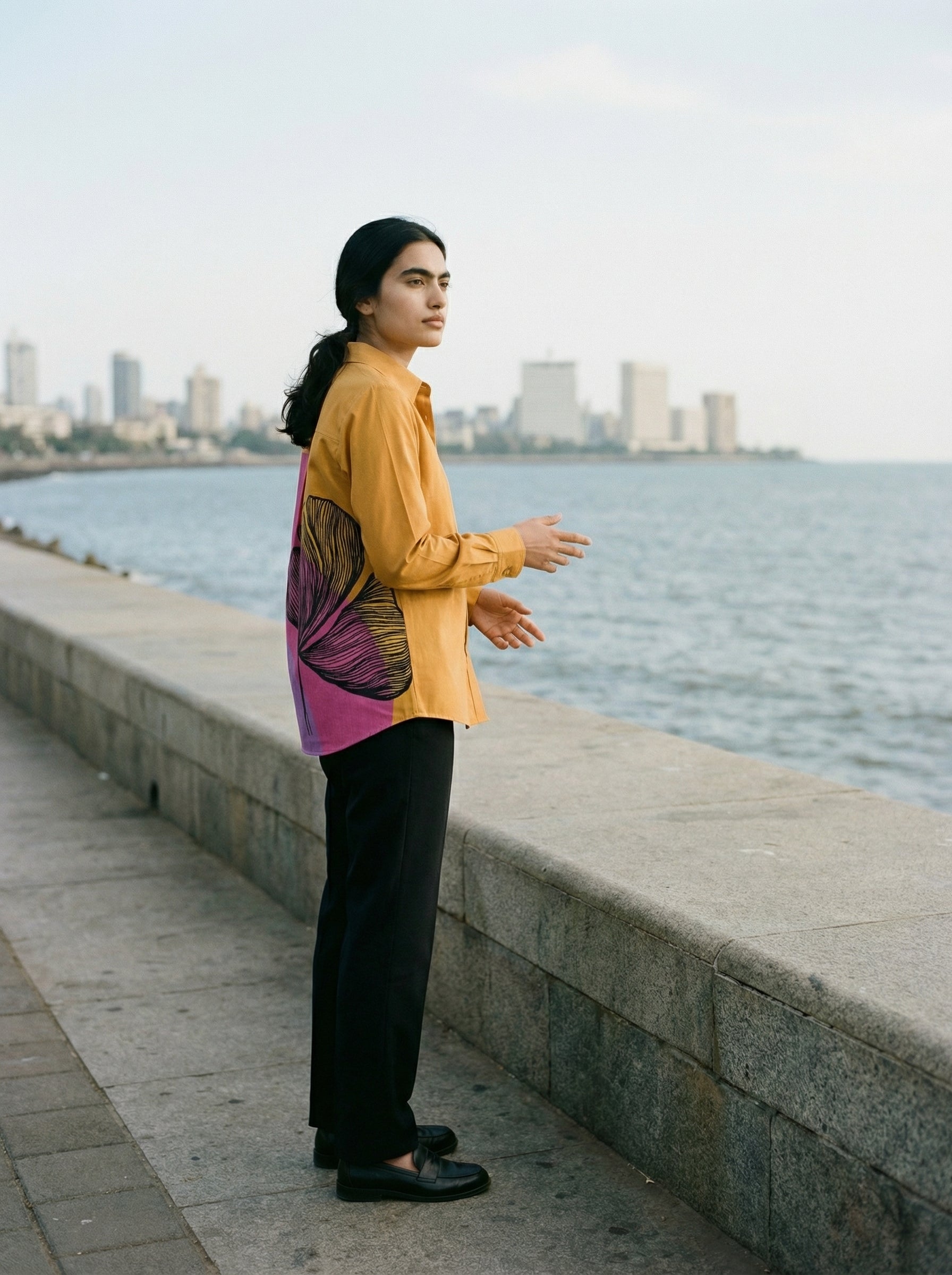 A striking mustard yellow shirt top featuring a bold contrast pink-purple panel at the back with an oversized black floral graphic for a statement finish.
