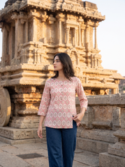 A stylish off-white top featuring soft pink ethnic-inspired motifs for a fresh everyday look