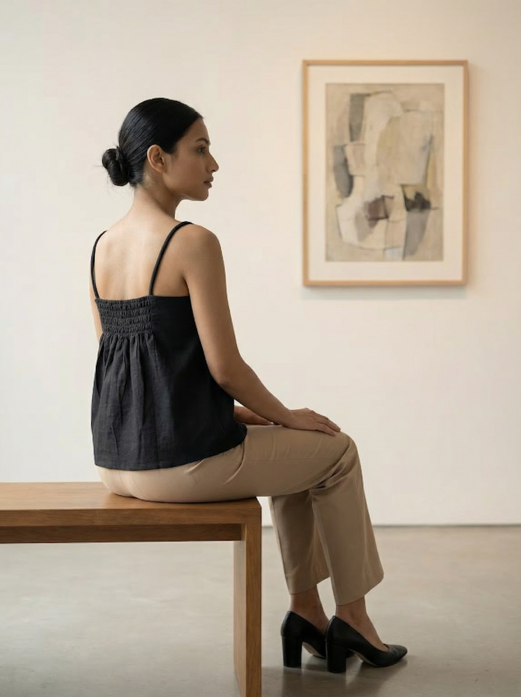 A sleek black sleeveless top designed with slim shoulder straps and subtle front pleat detailing for a clean, contemporary look.