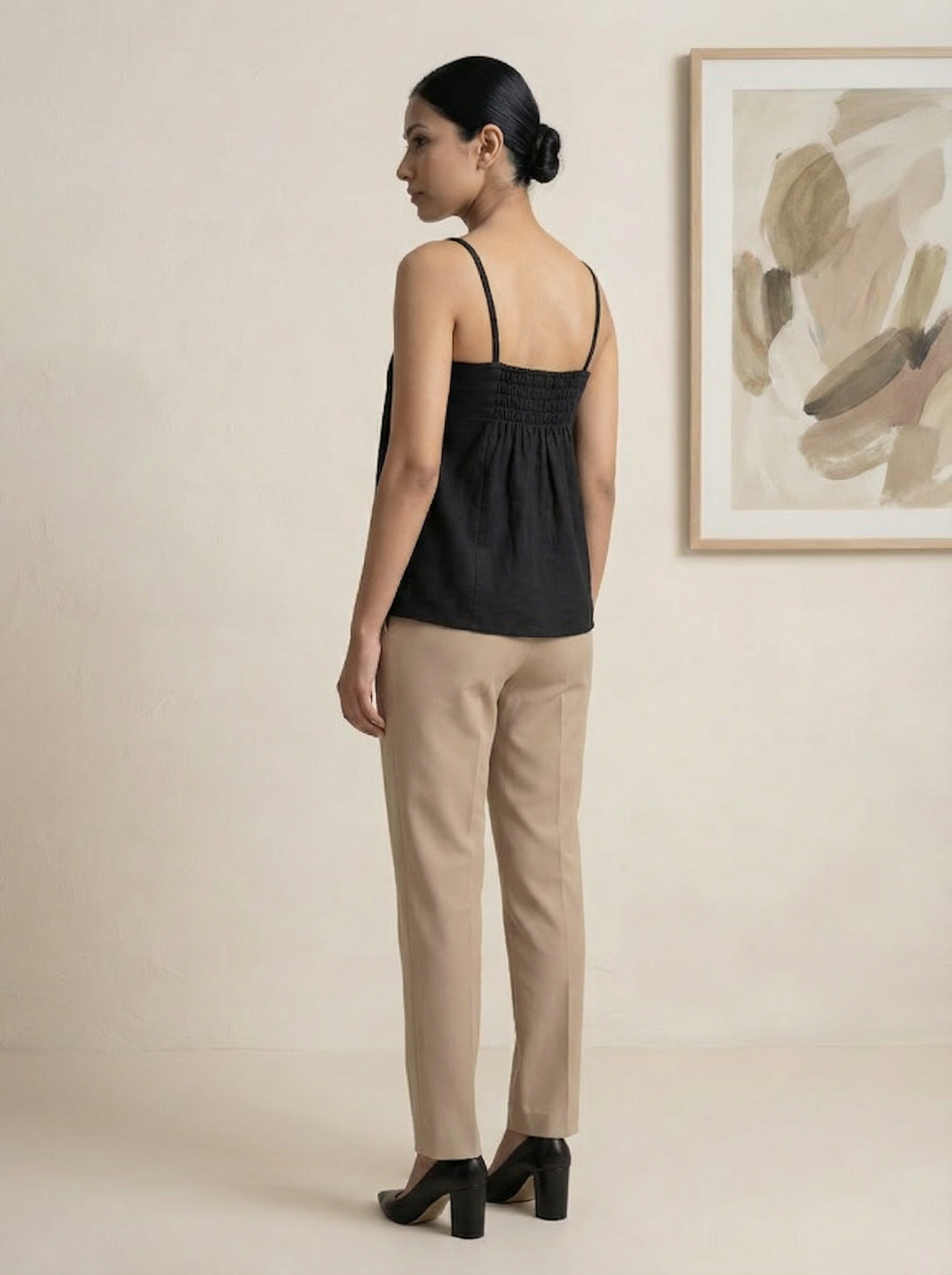A sleek black sleeveless top designed with slim shoulder straps and subtle front pleat detailing for a clean, contemporary look.