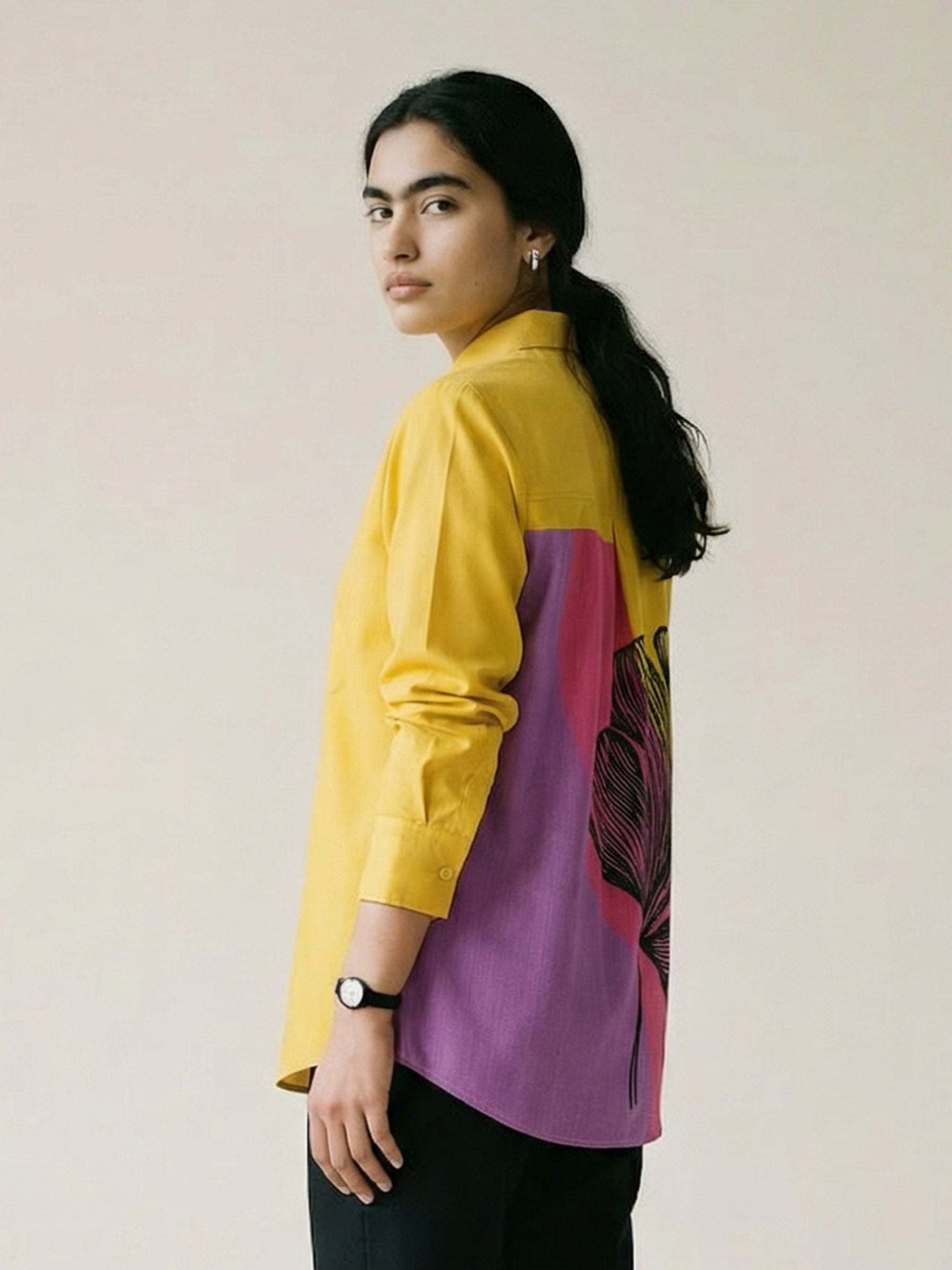 A striking mustard yellow shirt top featuring a bold contrast pink-purple panel at the back with an oversized black floral graphic for a statement finish.