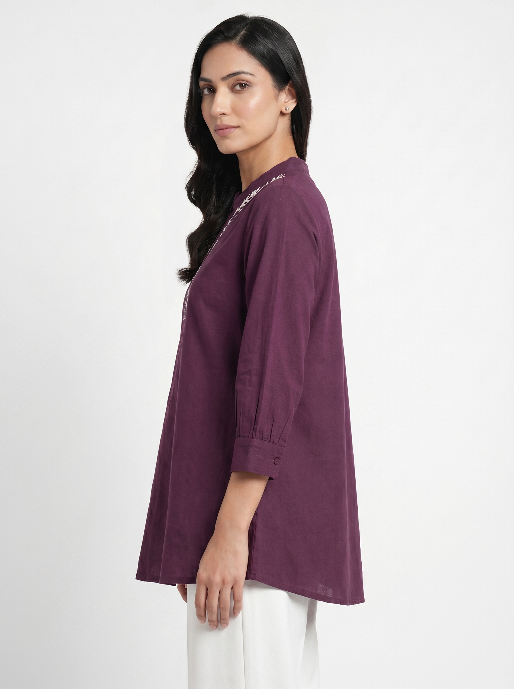 A graceful plum purple tunic top featuring delicate off-white floral vine embroidery around the neckline for an elegant handcrafted touch.