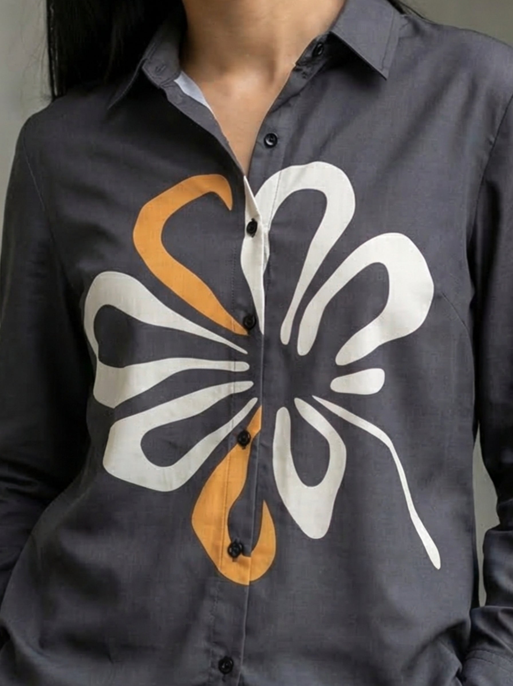 A contemporary charcoal grey shirt top featuring a bold white and mustard abstract floral graphic for a striking modern look. 