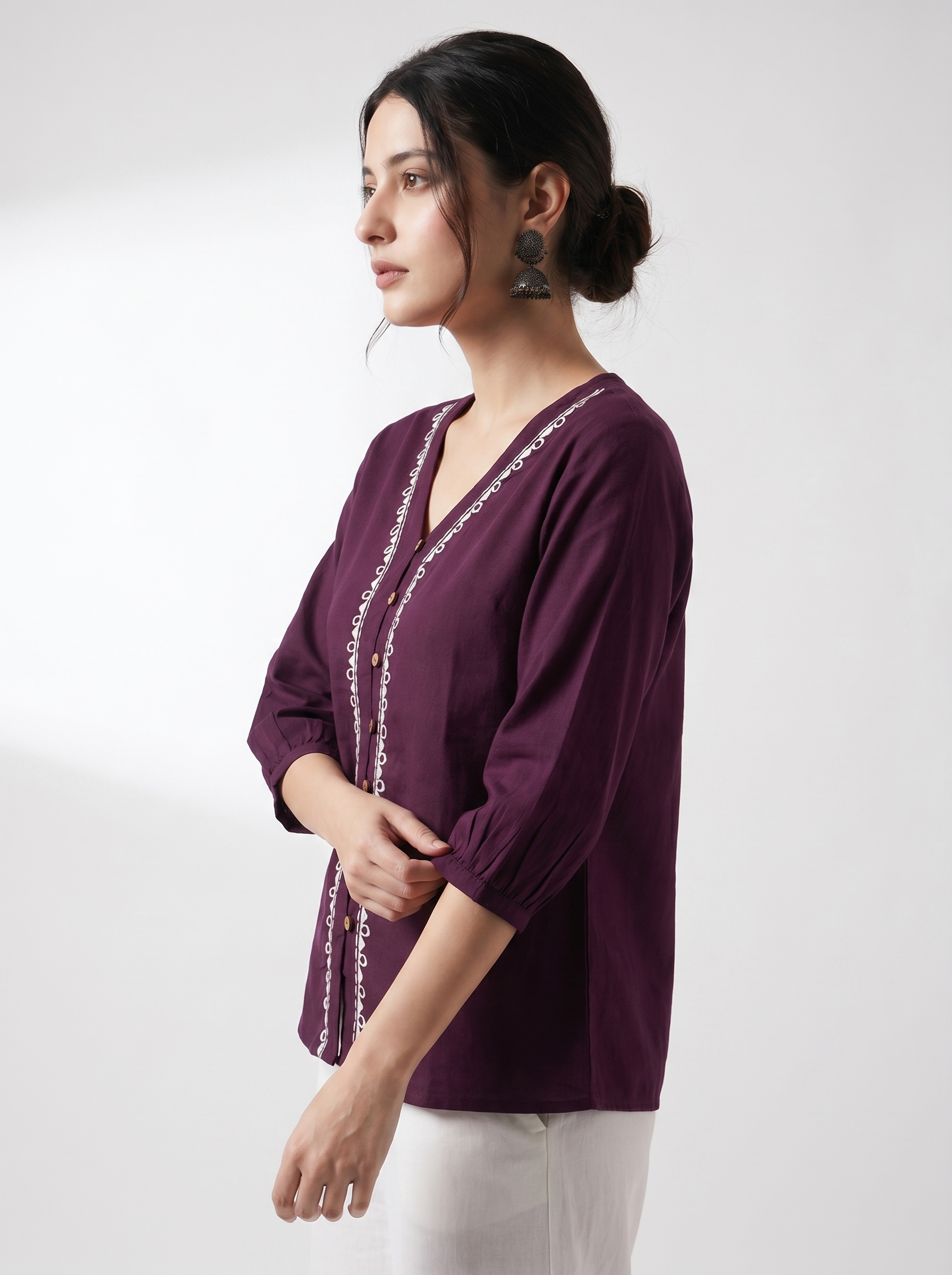 A rich plum purple top featuring elegant white contrast embroidery along the V-neckline and front placket for a refined statement look.