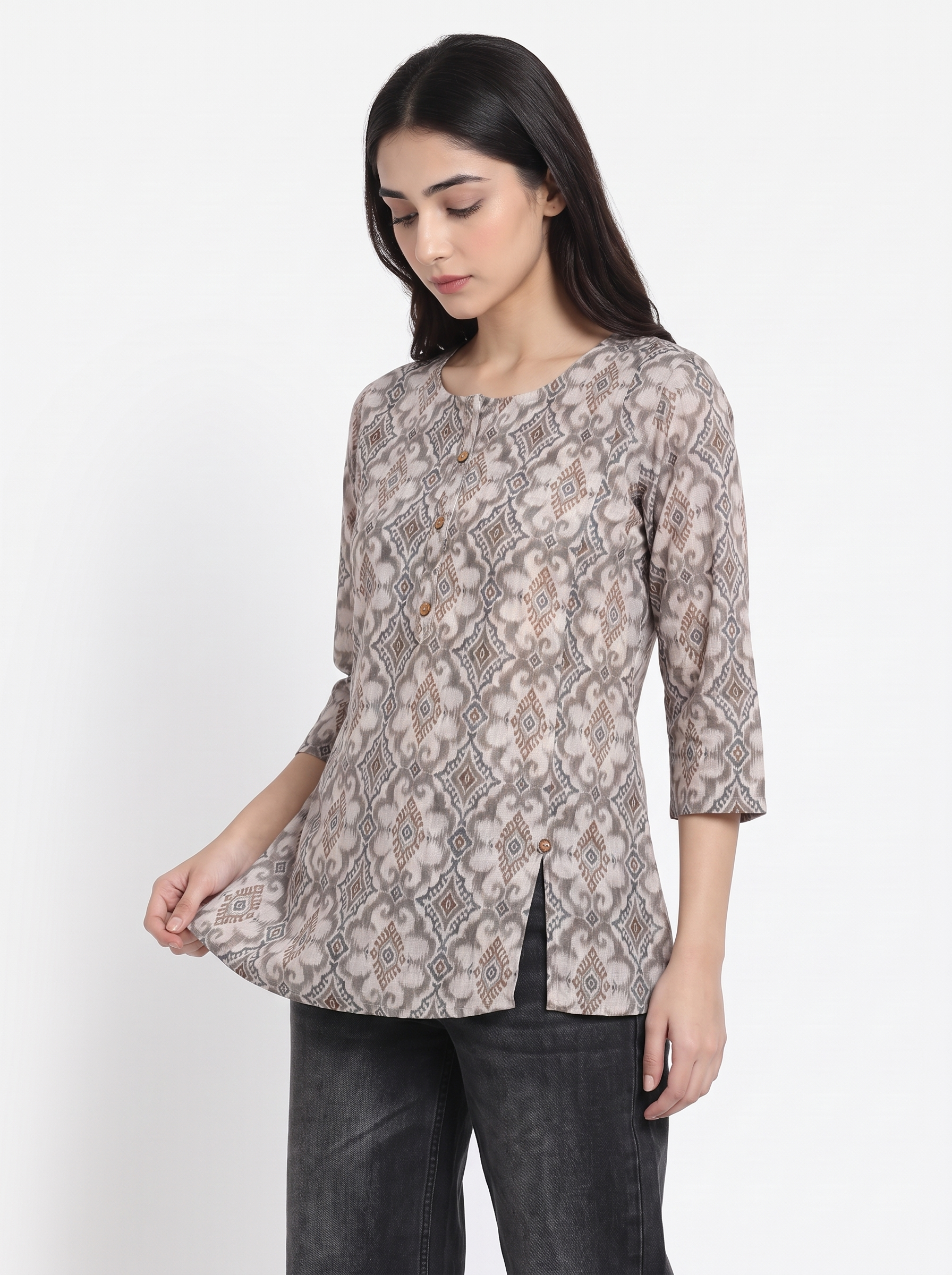 A woman wearing a three-quarter sleeve tunic top with a beige and brown snake print pattern, paired with dark gray jeans, photographed against a plain white studio background.