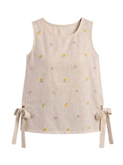 A sleeveless beige linen top with a small yellow and pink floral print, featuring side tie details at the hem, shown against a plain white background.