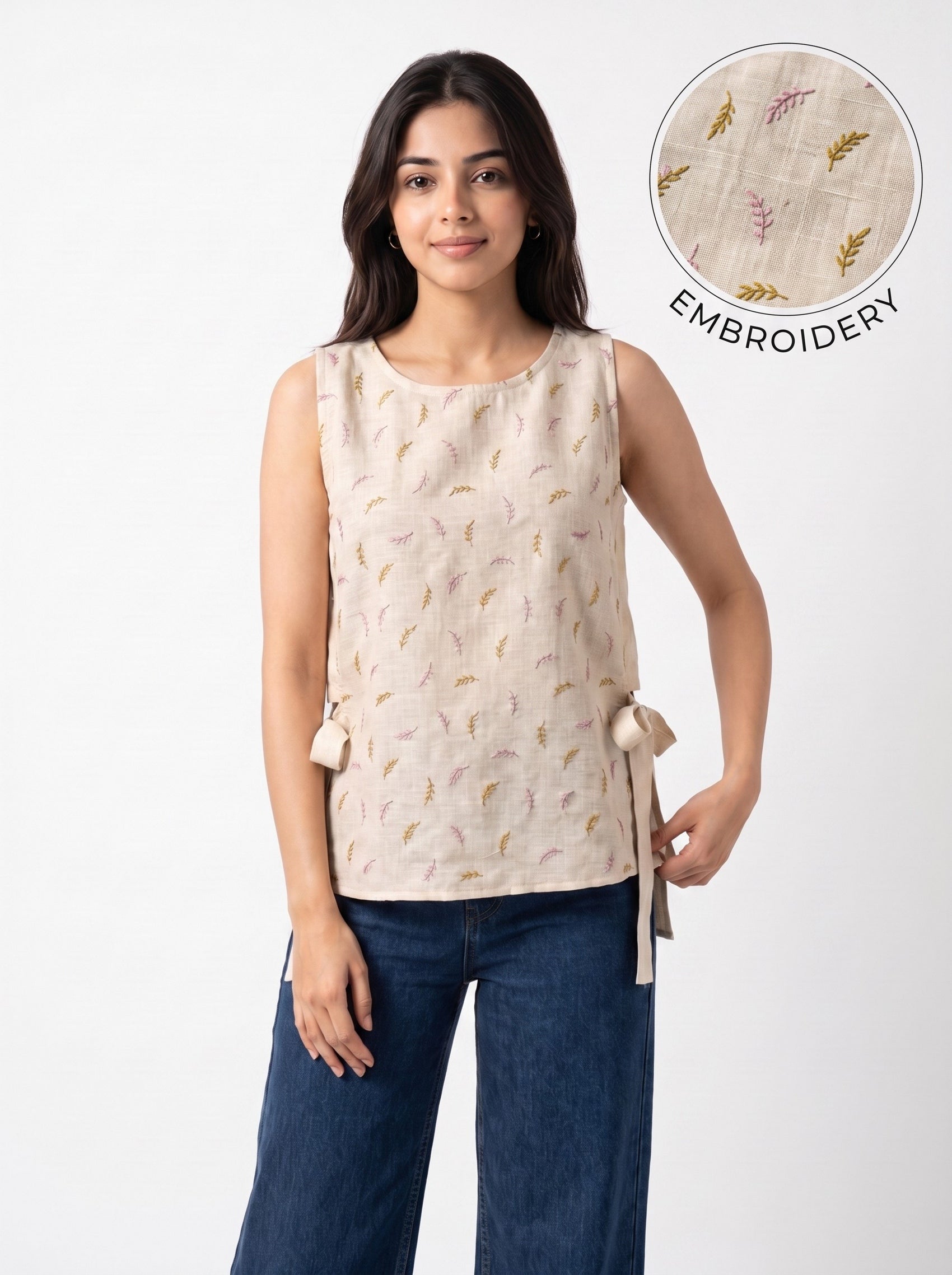 A woman modeling a sleeveless beige top with delicate embroidered details and side ties, paired with dark blue jeans. An inset circle in the top right shows a close-up of the embroidery texture with the text 'EMBROIDERY'.
