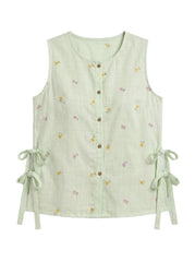 A sleeveless light green linen vest with a button-down front, tiny yellow and pink floral print, and side tie details, shown on a plain white background.