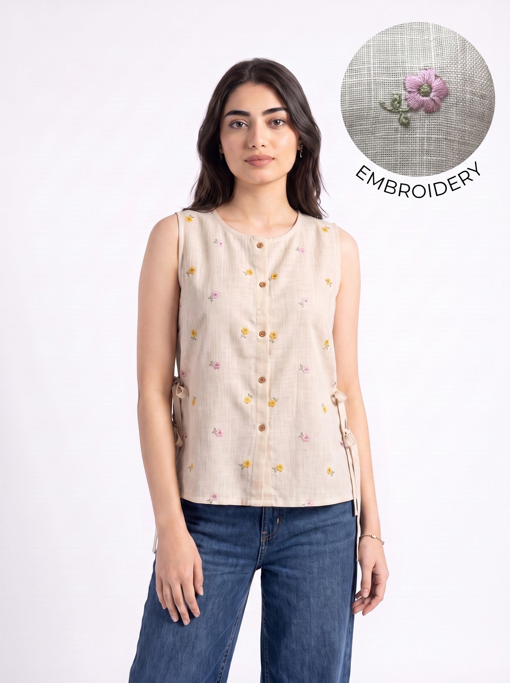 A woman modeling a sleeveless beige linen top with small embroidered floral details and brown buttons, paired with blue jeans. A circular inset in the top right shows a close-up of a matching beige fabric with a pink floral embroidery detail and the word 'EMBROIDERY'.