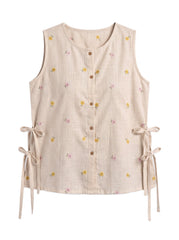 A sleeveless beige linen vest with a small yellow and pink floral print, brown button-down front, and side tie details, shown on a plain white background.