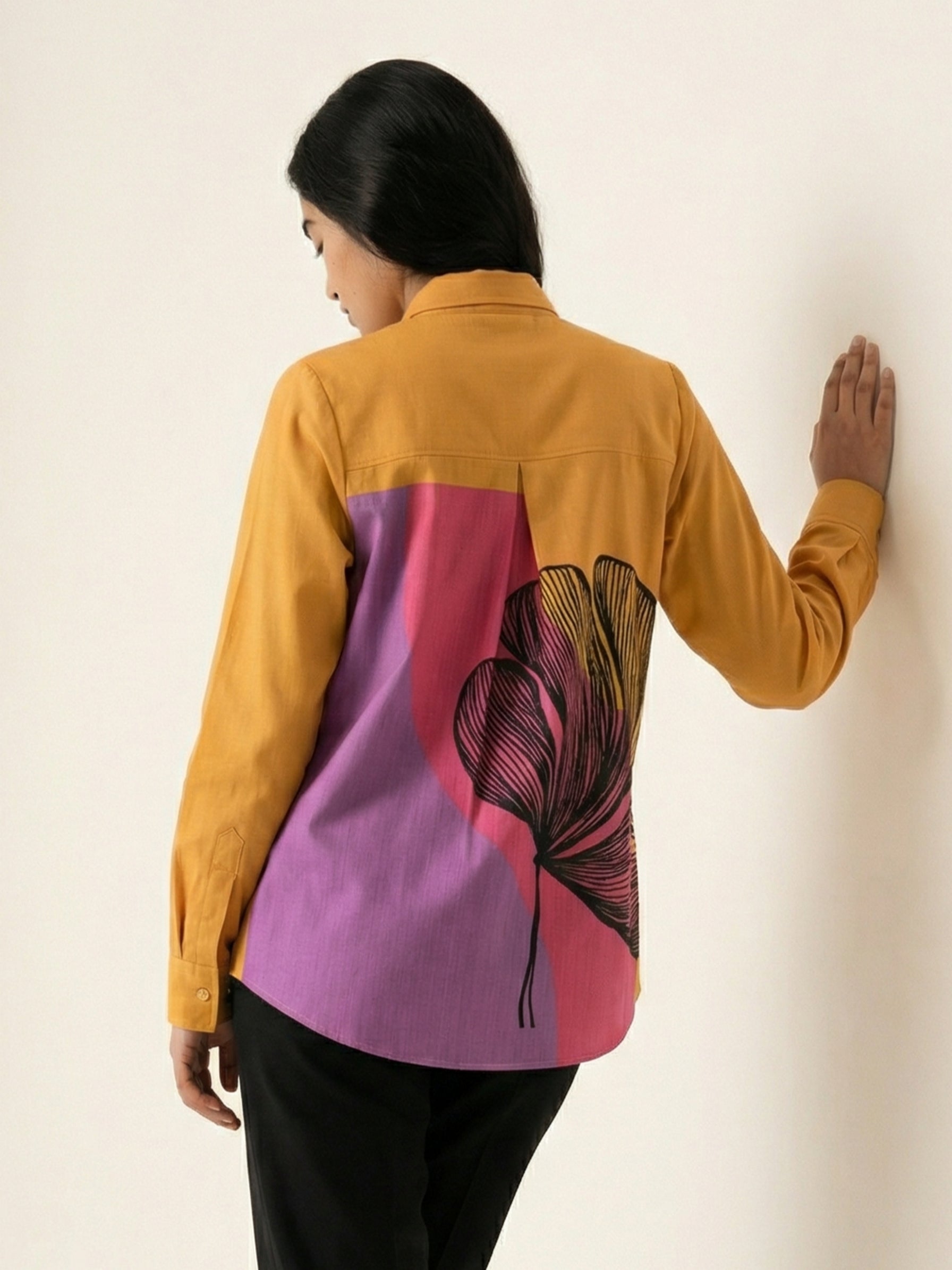 A striking mustard yellow shirt top featuring a bold contrast pink-purple panel at the back with an oversized black floral graphic for a statement finish.
