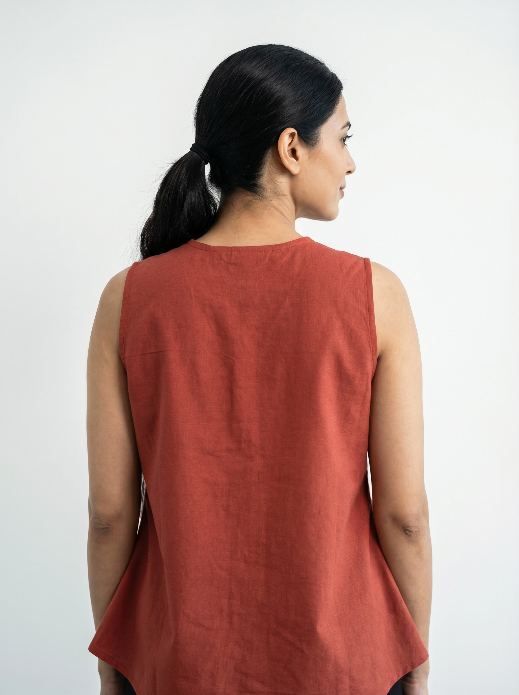 A stylish rust red sleeveless top featuring delicate off-white leaf vine embroidery along the V-neckline and front placket for a refined handcrafted look.