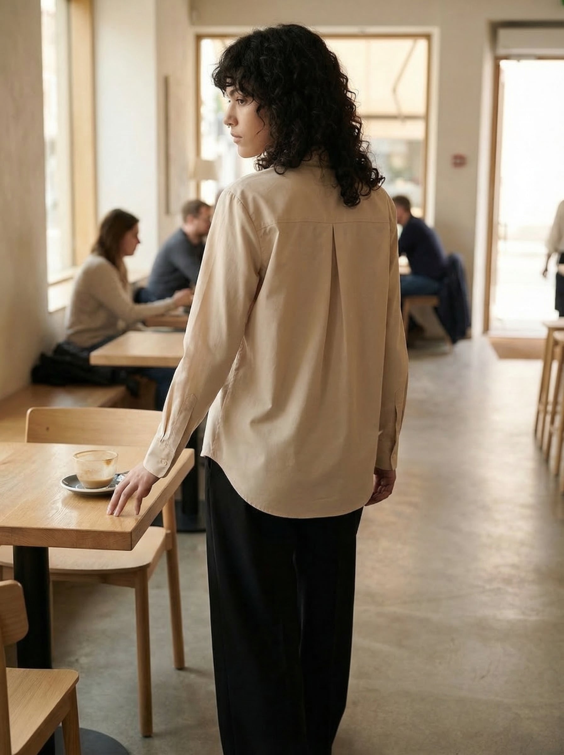 A refined cream shirt top featuring a striking teal ginkgo leaf graphic on the front for a clean artistic look.