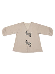 A beige linen long-sleeve top with black leaf embroidery on the front, displayed flat against a white background.
