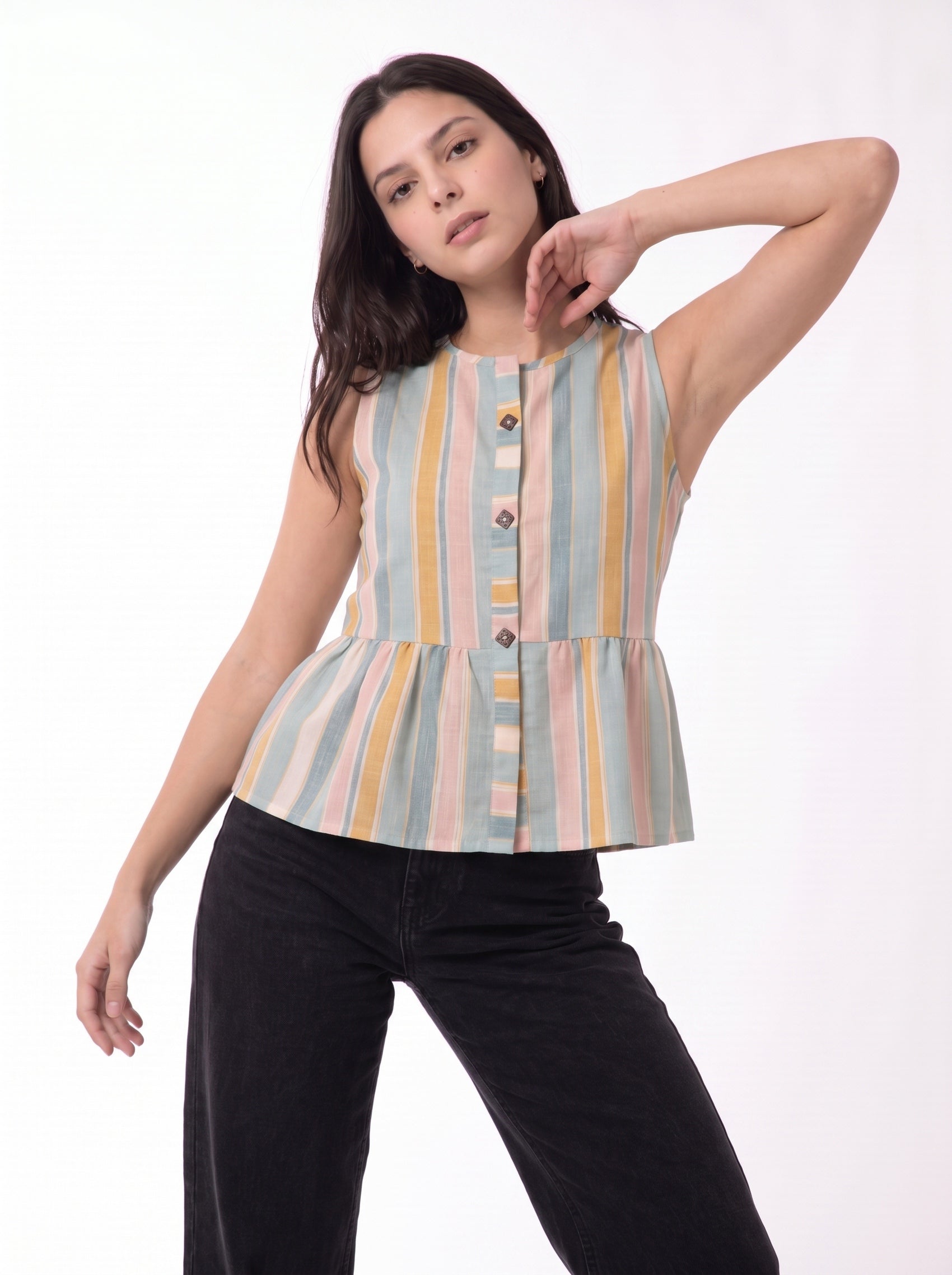 A woman modeling a sleeveless peplum top with vertical pastel stripes in blue, yellow, pink, and beige, paired with black pants, against a plain white studio background.