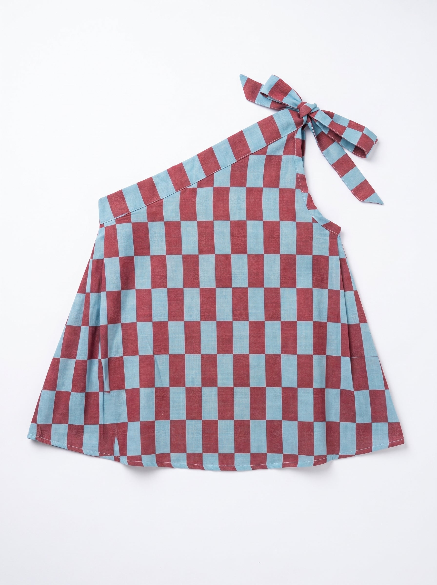 A one-shoulder dress featuring a red and light blue checkerboard pattern, with a tie detail at the shoulder, laid flat on a white background.