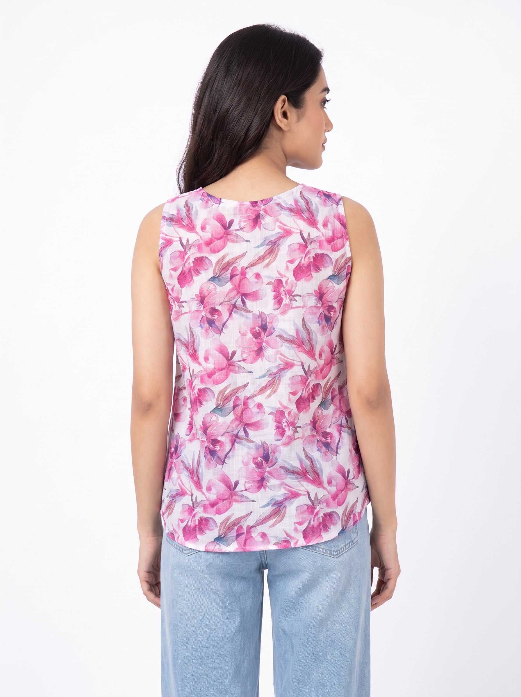 A woman shown from the back wearing a sleeveless top with a pink and white floral print, paired with light blue jeans, against a plain white background.